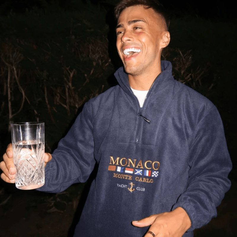 Men’s half zip sweater with embroidered motif, long sleeves, and straight hem, worn by model