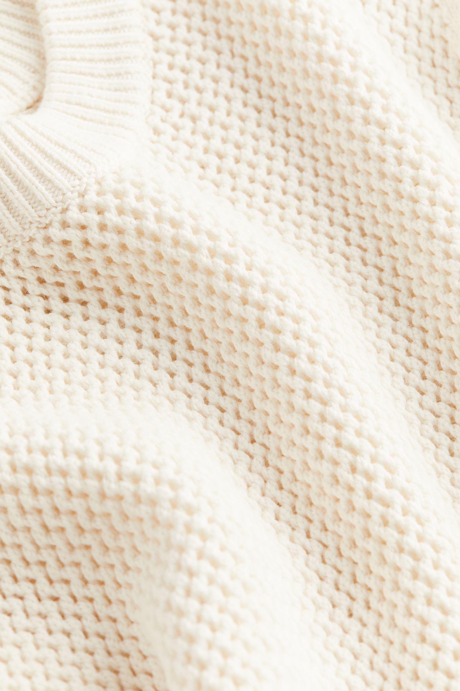 Knit sweater with visible texture and ribbed edges, laid flat