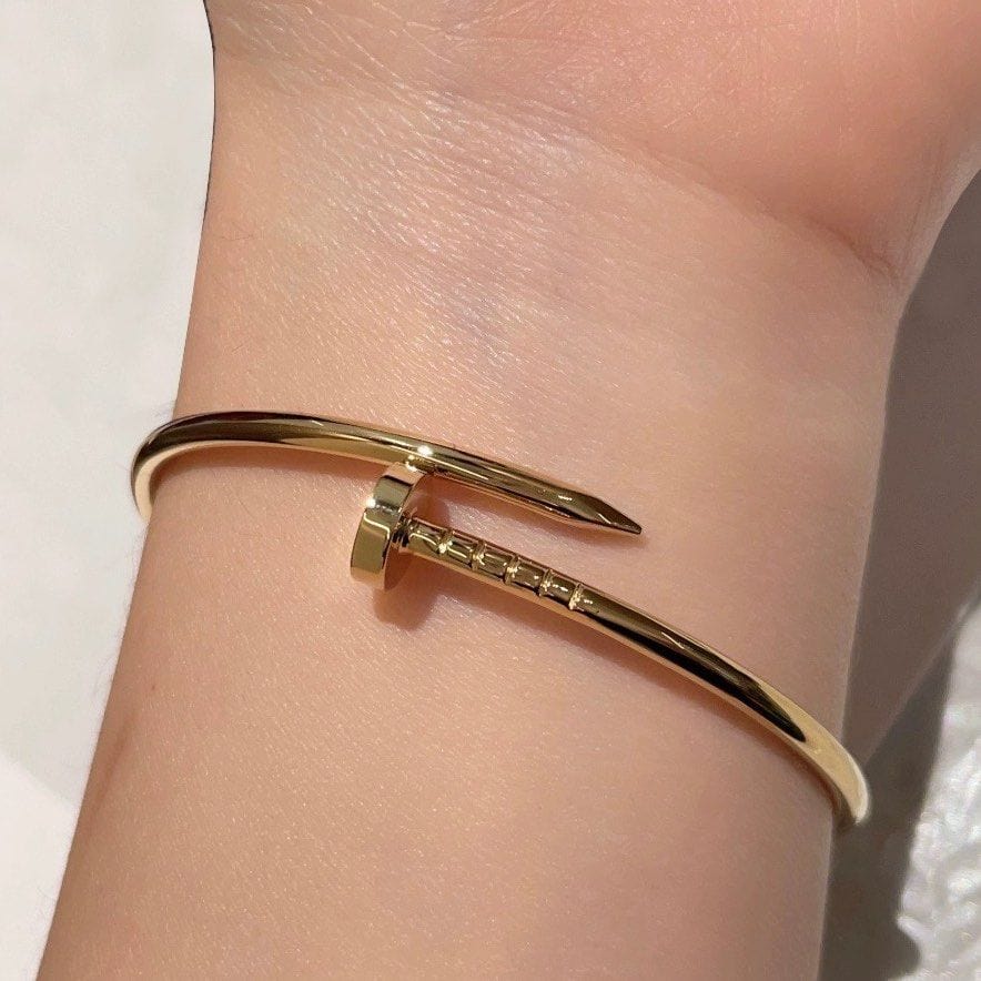 Model wearing open cuff bracelet with nail-inspired wraparound design