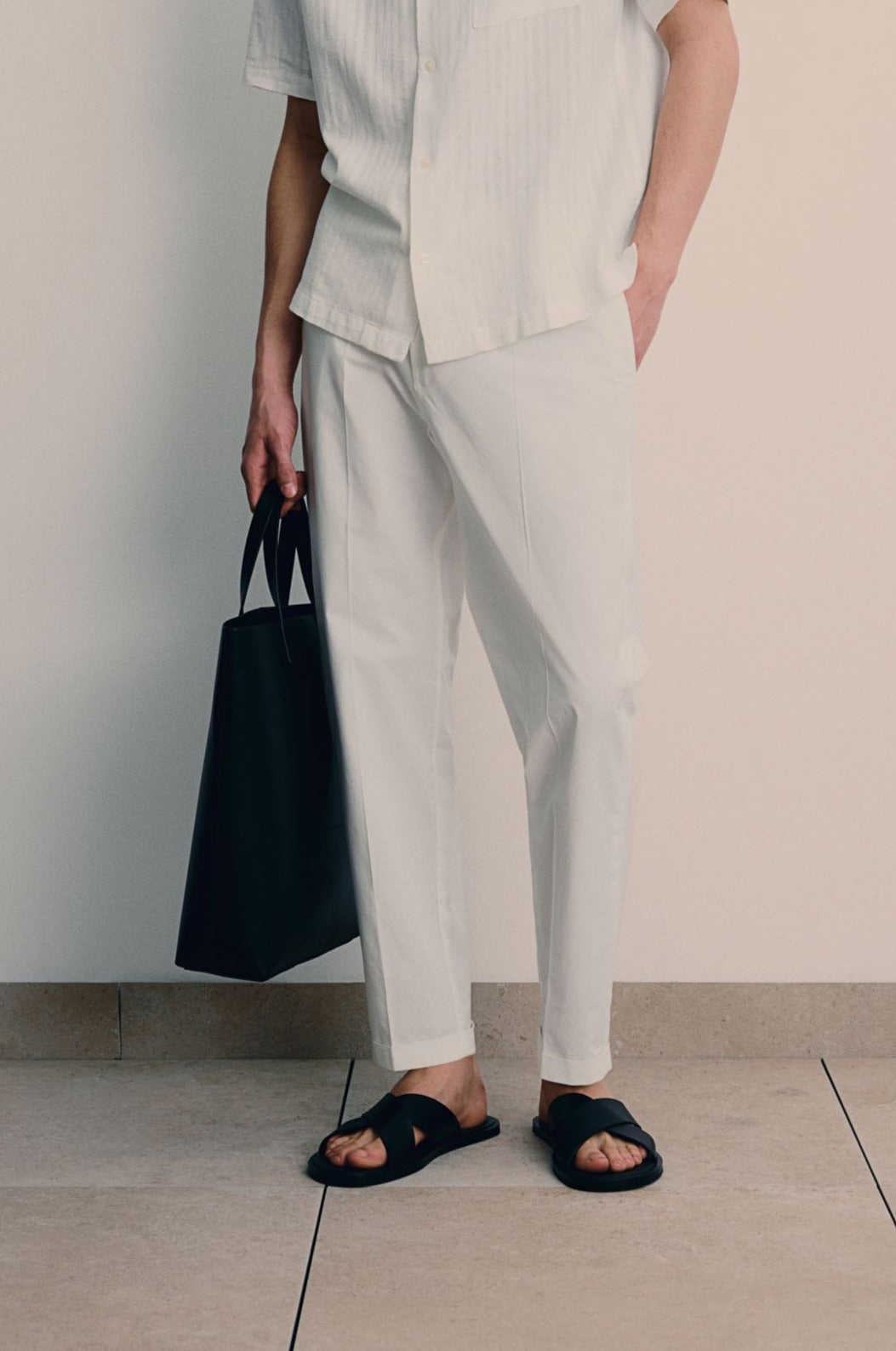 Tapered trousers with back pockets and visible hemline, worn by model