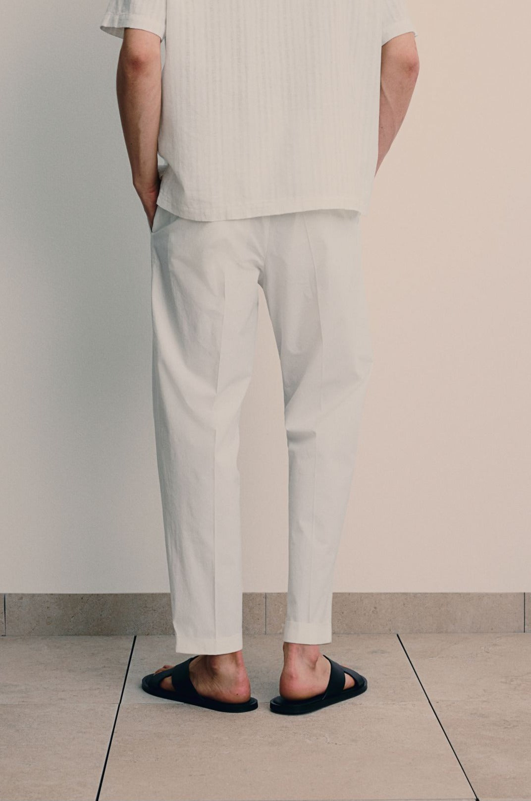 Men’s pants with button front and stitched crease lines, shown on model